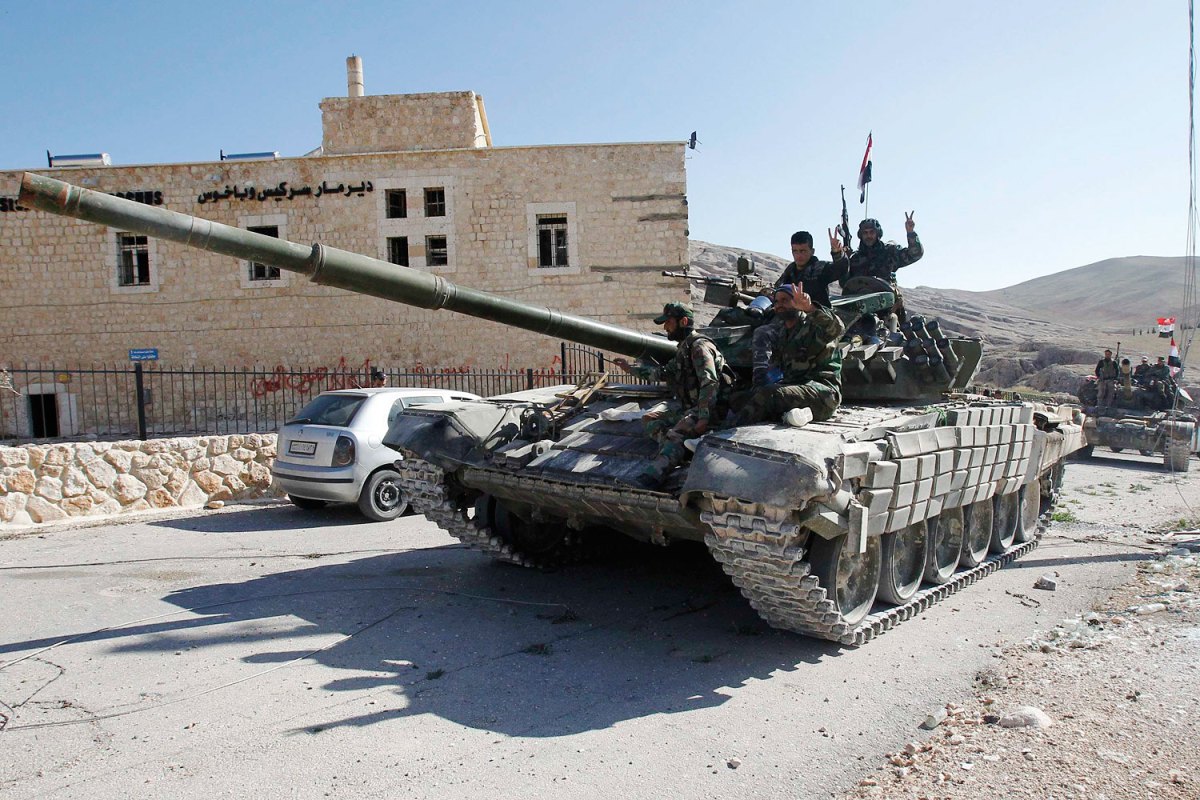 Soldiers loyal to President al-Assad gesture from tank, as they pass Mar Bacchus Sarkis monastery, in Maloula village, northeast of Damascus