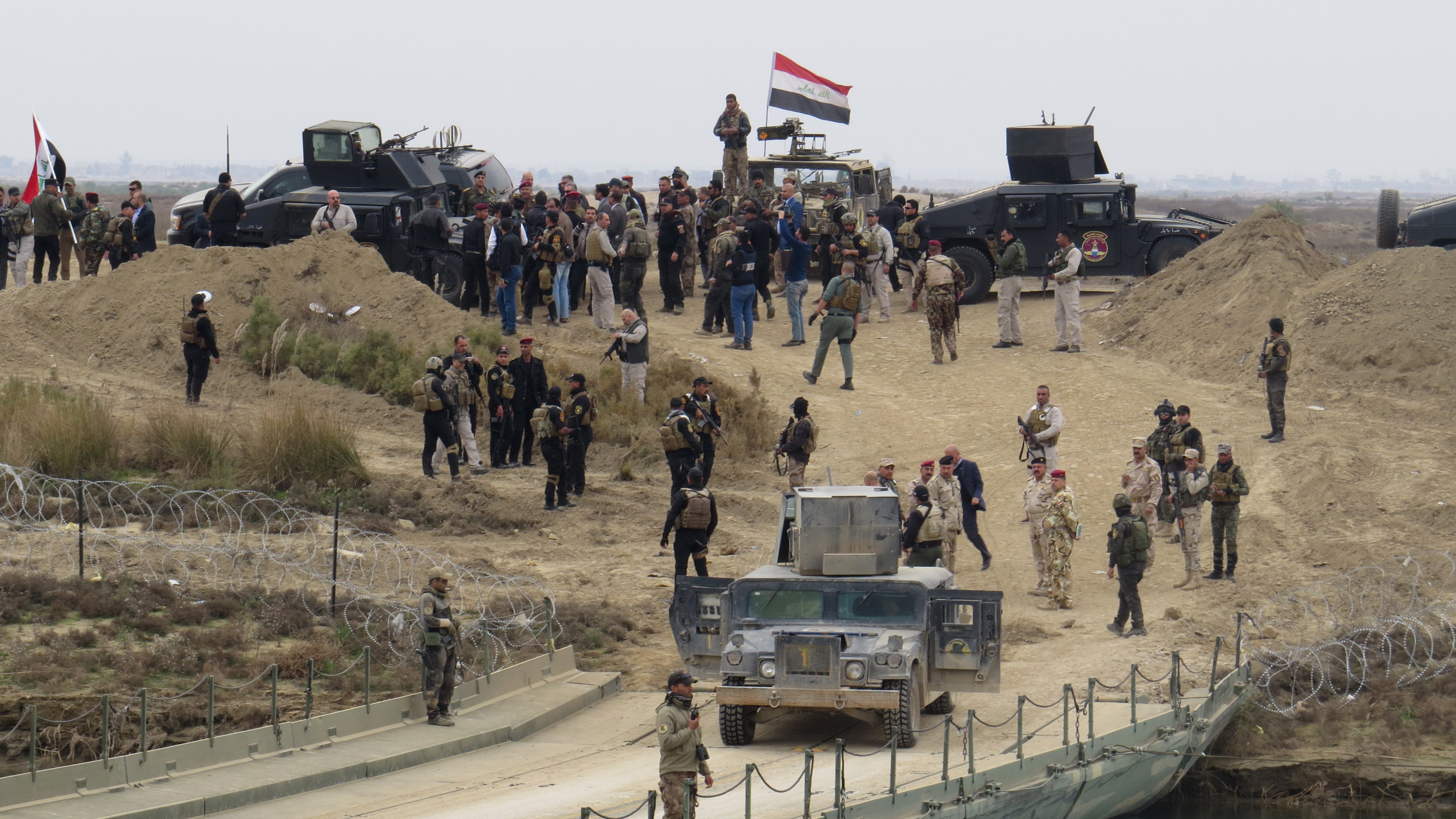 Iraqi security forces gather near a temporary bridge built by the corps of engineers in the Iraqi army south of Ramadi, during a visit by Iraqi Prime Minister Haider al-Abadi on December 29, 2015, after government forces recaptured the city from the Islamic State jihadist group. Abadi visited Ramadi, which lies around 100 kilometres (60 miles) west of Baghdad and is the capital of the province of Anbar, a day after federal forces announced the liberation of the city from the Islamic State group, clinching a landmark victory.  AFP PHOTO / STR / AFP / STR        (Photo credit should read STR/AFP/Getty Images)
