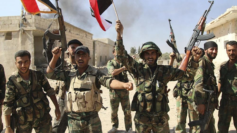 FILE - In this file photo taken on Sunday, Oct. 11, 2015, Syrian soldiers waving Syrian flags celebrate the capture of Achan, Hama province, Syria. The ever-growing, secret defense budgets and poor oversight of militaries in the Middle East make them susceptible to corruption and more vulnerable to extremist violence, a watchdog group warned. (Alexander Kots/Komsomolskaya Pravda via AP, File)